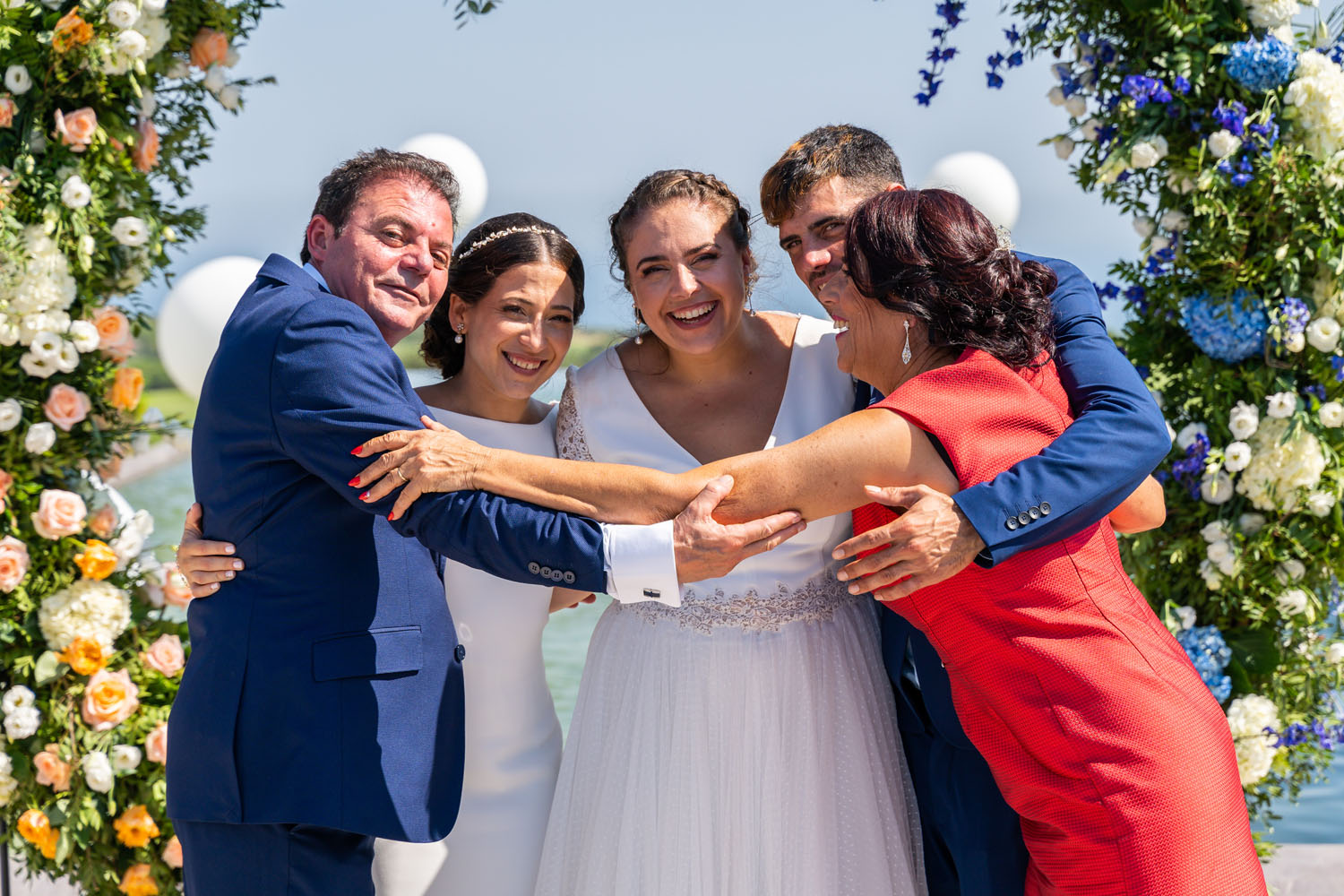 Novias con sus padres dándose un abrazo