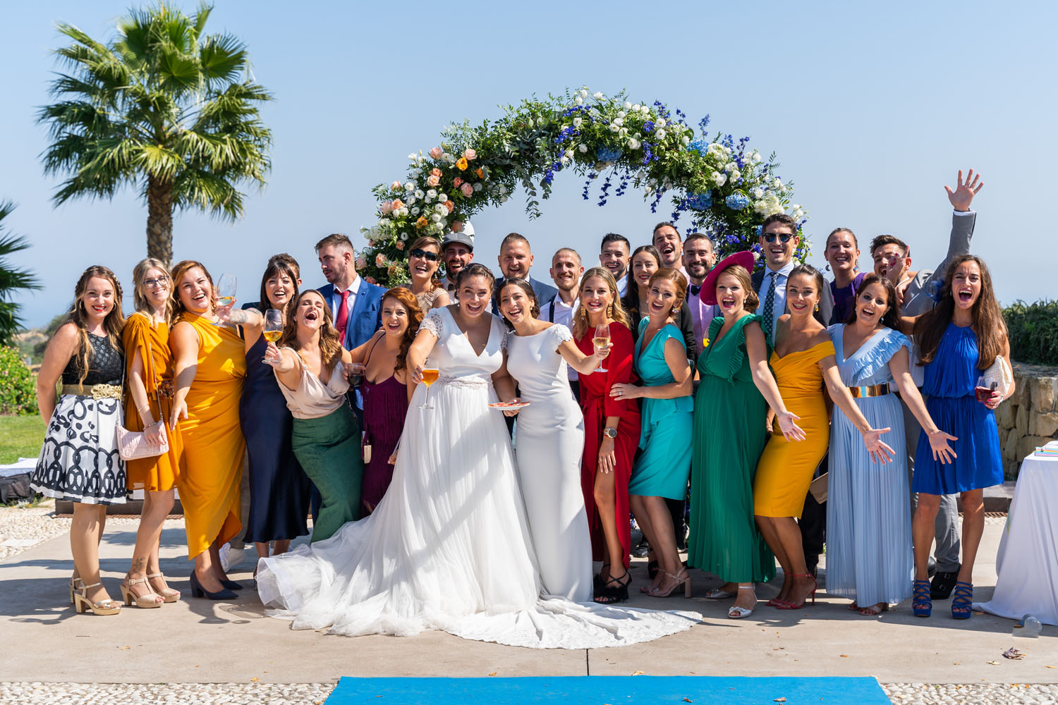 Fotos de grupo de amigos en una boda con un arco de flores de fondo