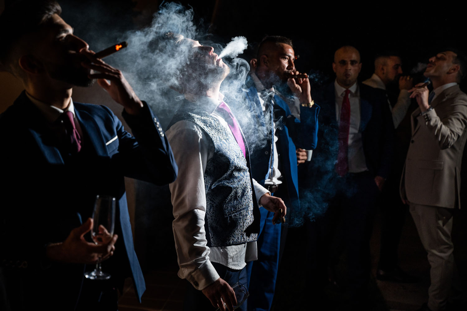 Invitados y novio fumando puro de boda